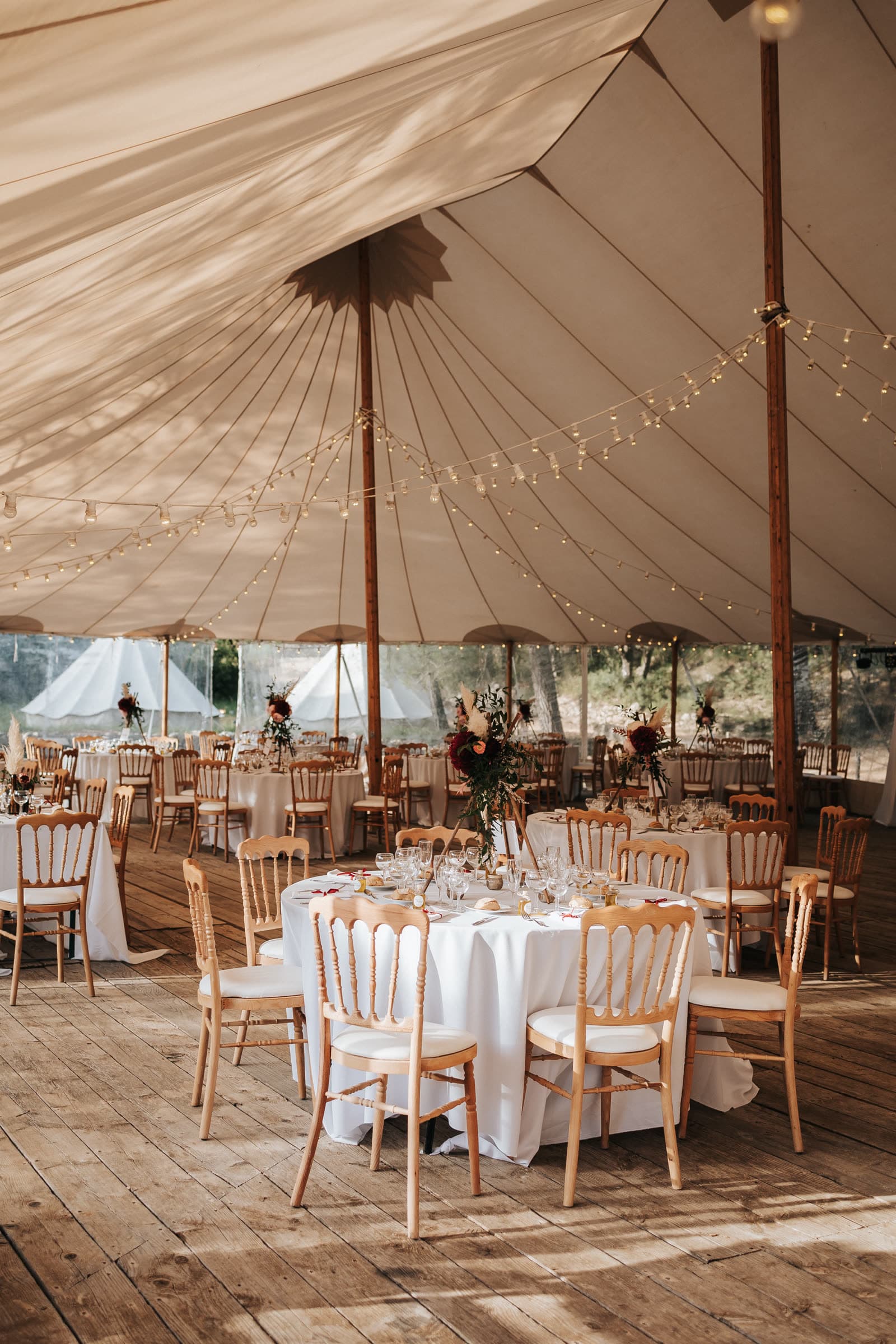 Longue table de banquet sous voilage et guirlandes lumineuses